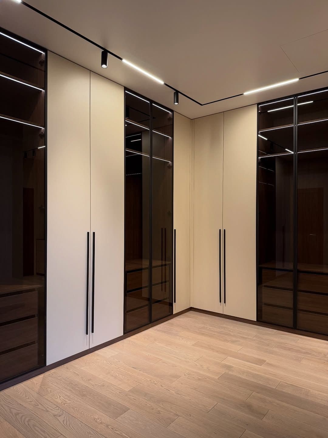 Smoked-glass walk-in dressing room under magnetic track lighting - bespoke joinery by Royalwoods Interiors, Nairobi