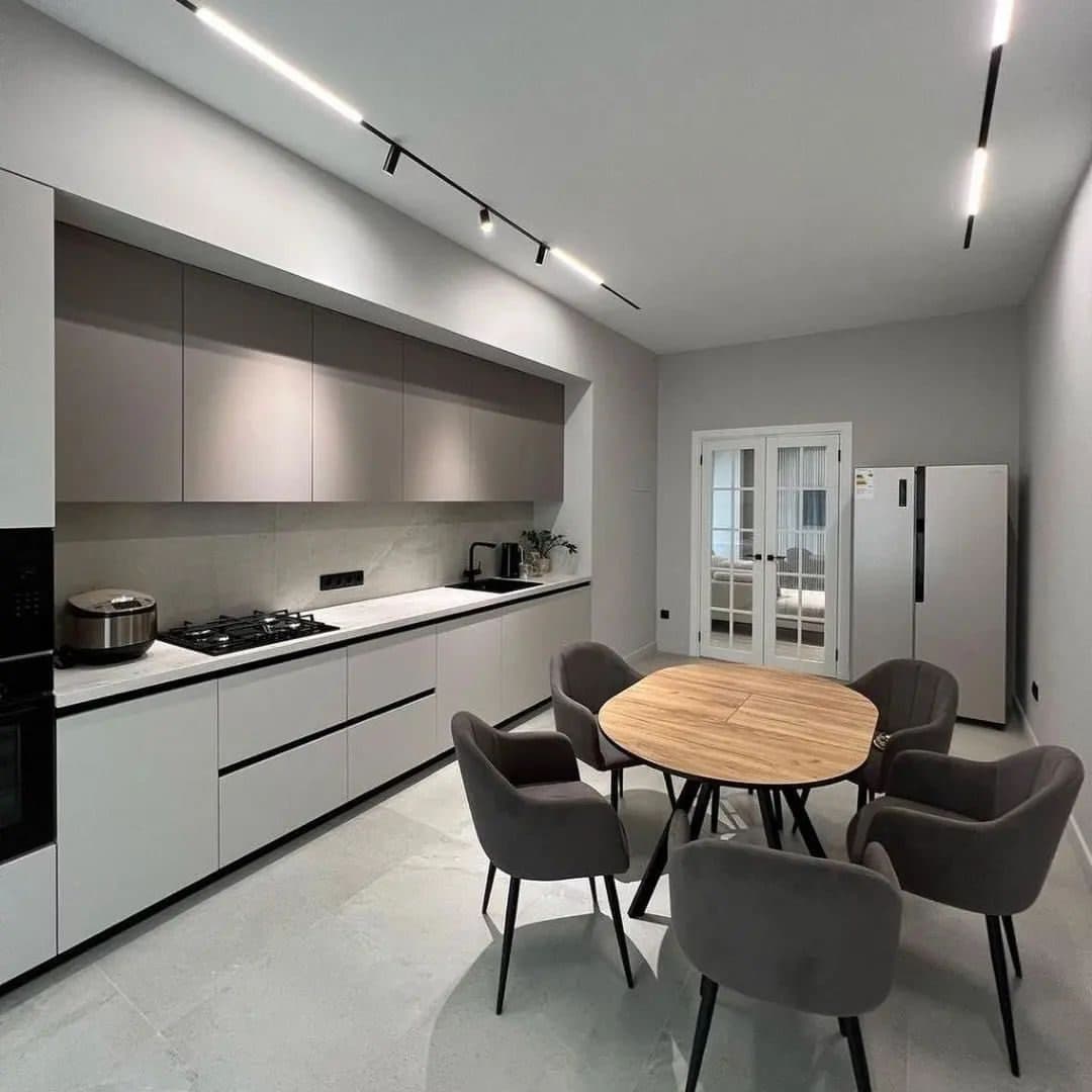 Greige kitchen under magnetic track lighting, splashback in honed stone - bespoke joinery by Royalwoods Interiors, Nairobi