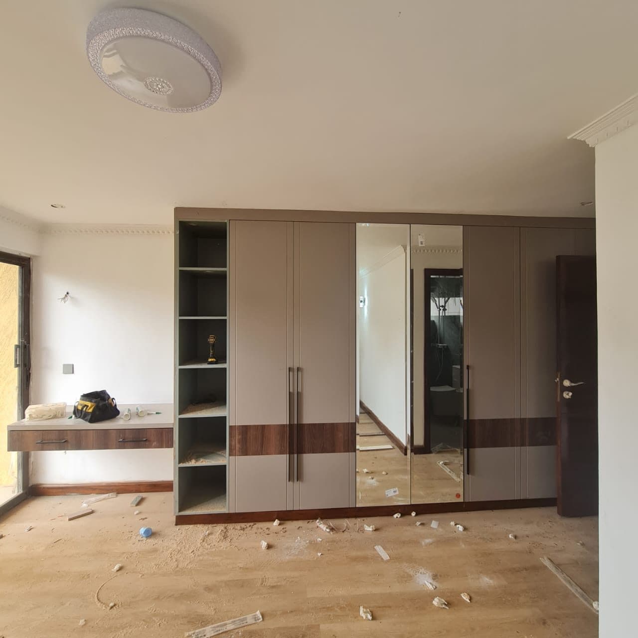 Mirror-fronted wardrobe during installation, trim and scribing in progress - bespoke joinery by Royalwoods Interiors, Nairobi