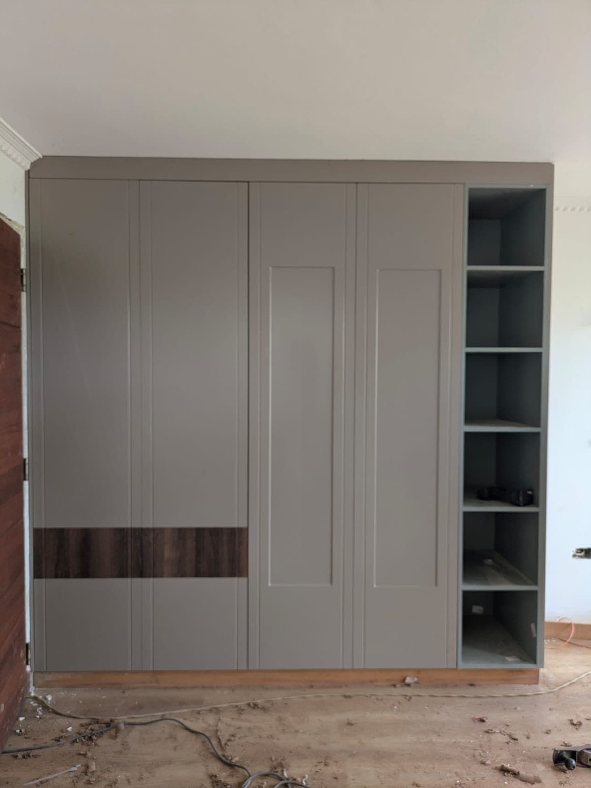 Sage-grey wardrobe with open shelf column during second-fix works - bespoke joinery by Royalwoods Interiors, Nairobi
