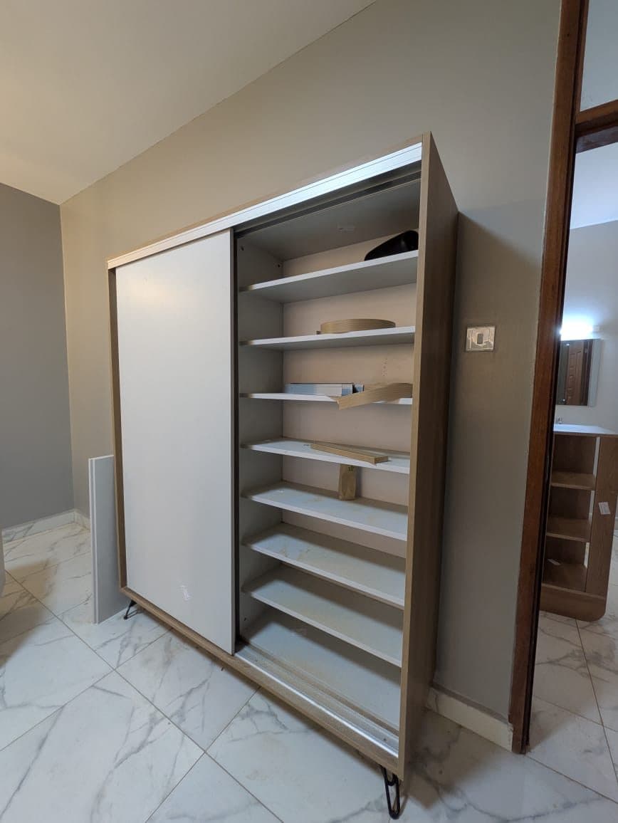 Bespoke sliding-door shoe cabinet, doors open to show full-depth shelving - bespoke joinery by Royalwoods Interiors, Nairobi